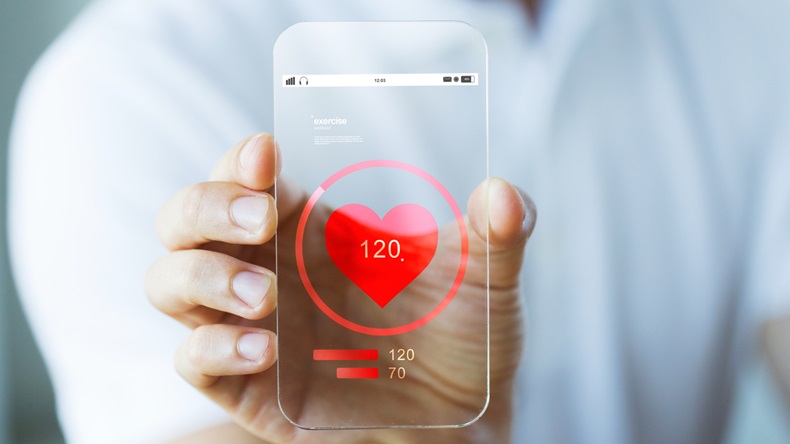 business, technology, health care and people concept - close up of male hand holding and showing transparent smartphone with heart rate icon