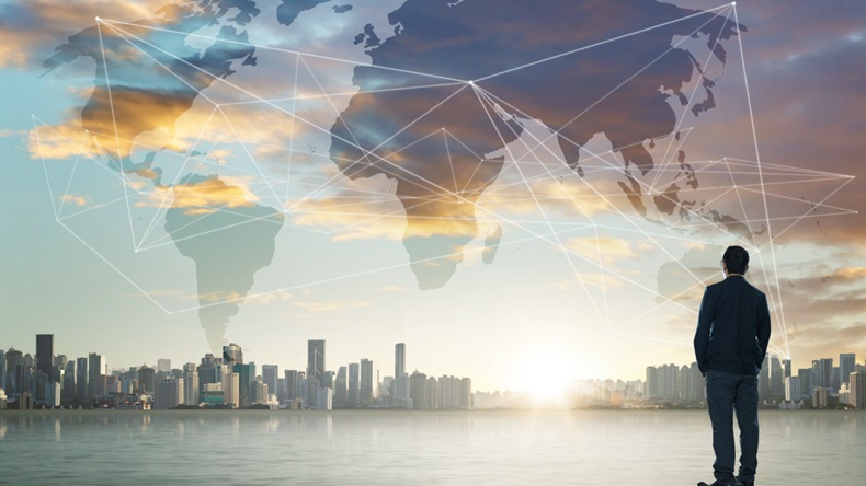 International business concept with businessman and digital map superimposed on a city skyline background.