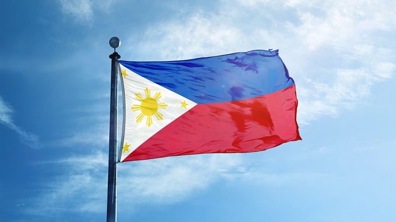 Flag of Philippines files against a lightly clouded blue sky