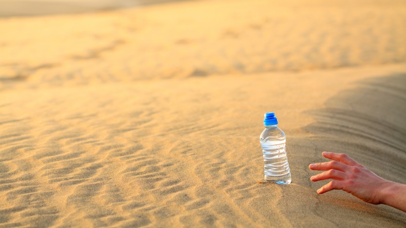 Hand try to catch the bottle of water on sand desert in hot temperature. Concept of to die of thirst. - Image 