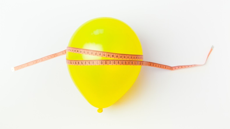 Balloon tied measuring tape on white background. Weight loss, slim body, healthy lifestyle concept.