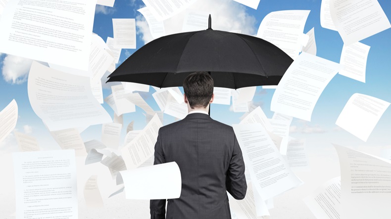 businessman is standing under the papers rain.