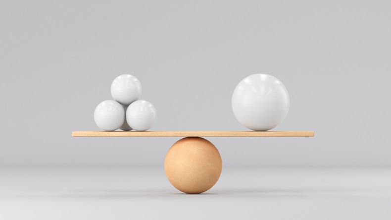 One big ball and many small ones. On wooden scales on a white background. 