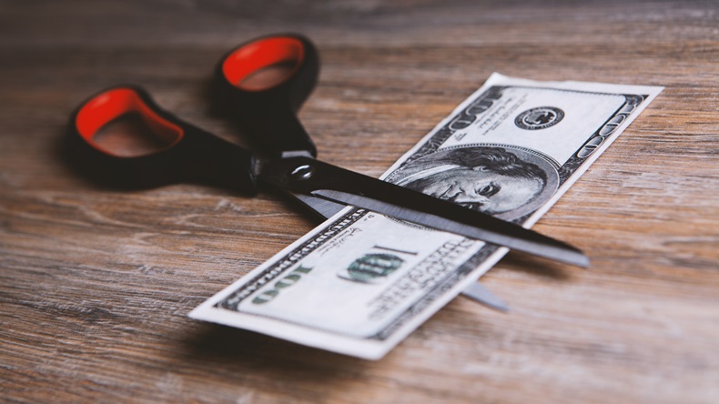 Scissors cut a $100 bill in half