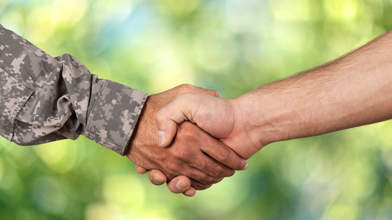 Photo of two people shaking hands. One of them is wearing a military uniform.