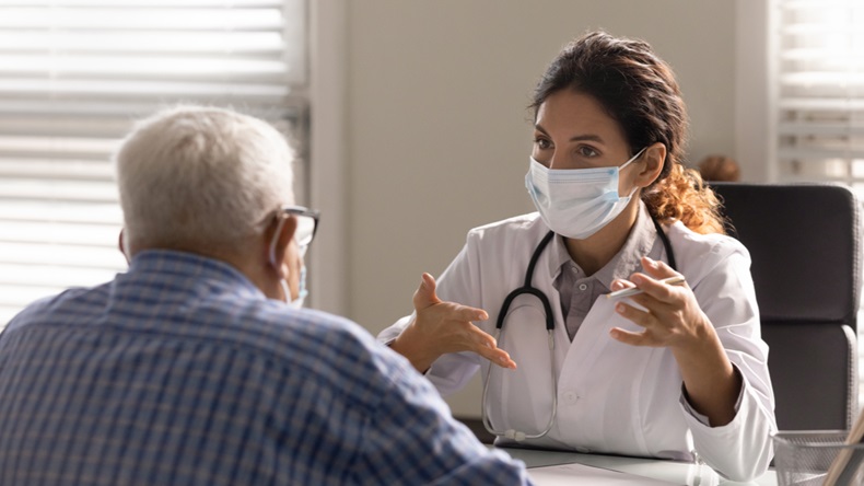 Close up female doctor wearing face mask consulting mature patient