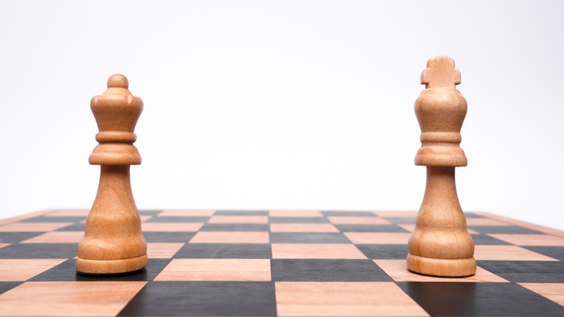 A king and a queen stand in isolation at different ends of a chessboard. 