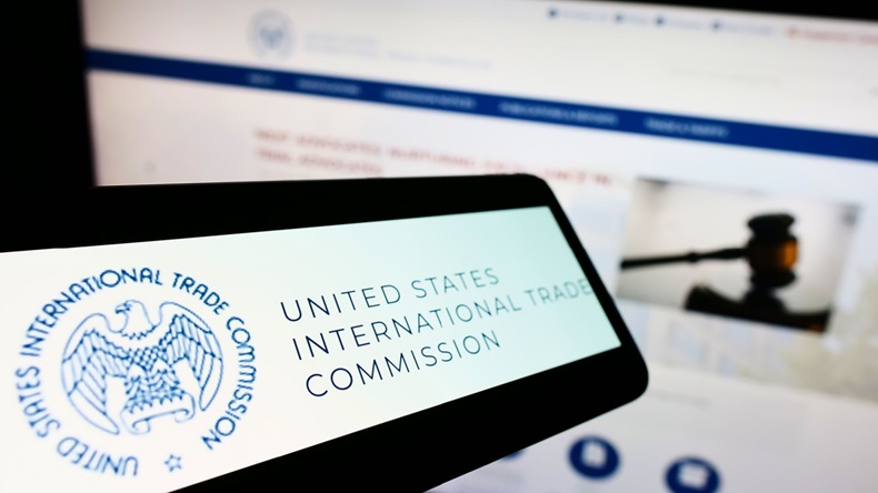 Smartphone with logo of American International Trade Commission (USITC) on screen in front of website.