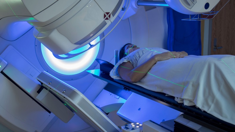 Picture of woman in scrubs receiving radiation therapy.