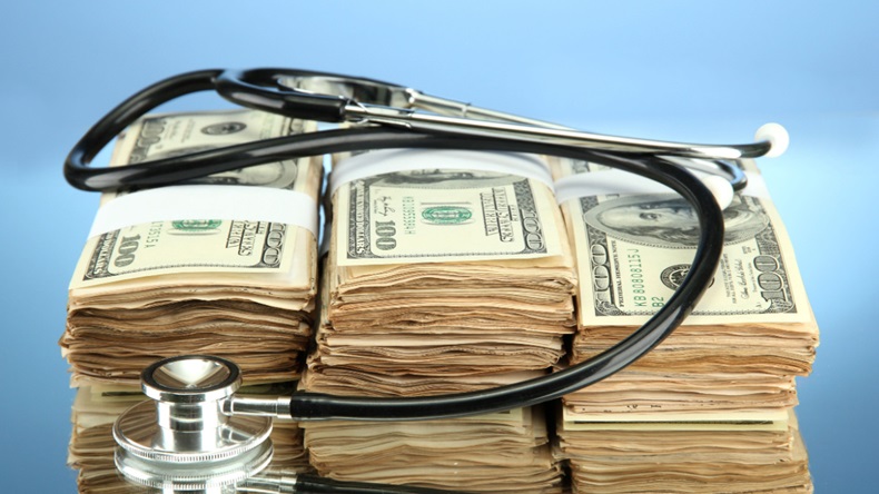 Stethoscope and stacks of dollar bills on a blue background.