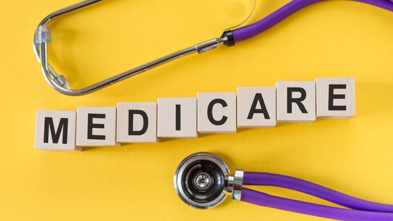 "Medicare" written out on wood blocks on a yellow background. A stethescope surrounds the letters in the background.
