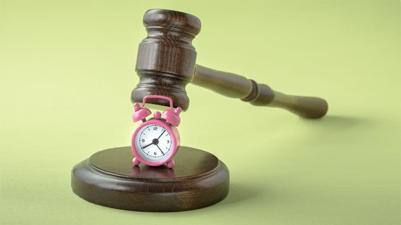 Gavel and alarm clock on green background. Postponement of a hearing, trial or auction end time of the concept