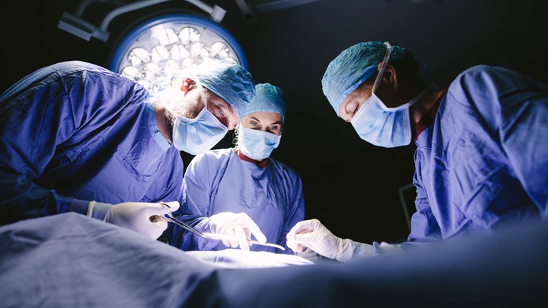 Group of surgeons doing surgery in hospital operating theater. Medical team doing critical operation. -